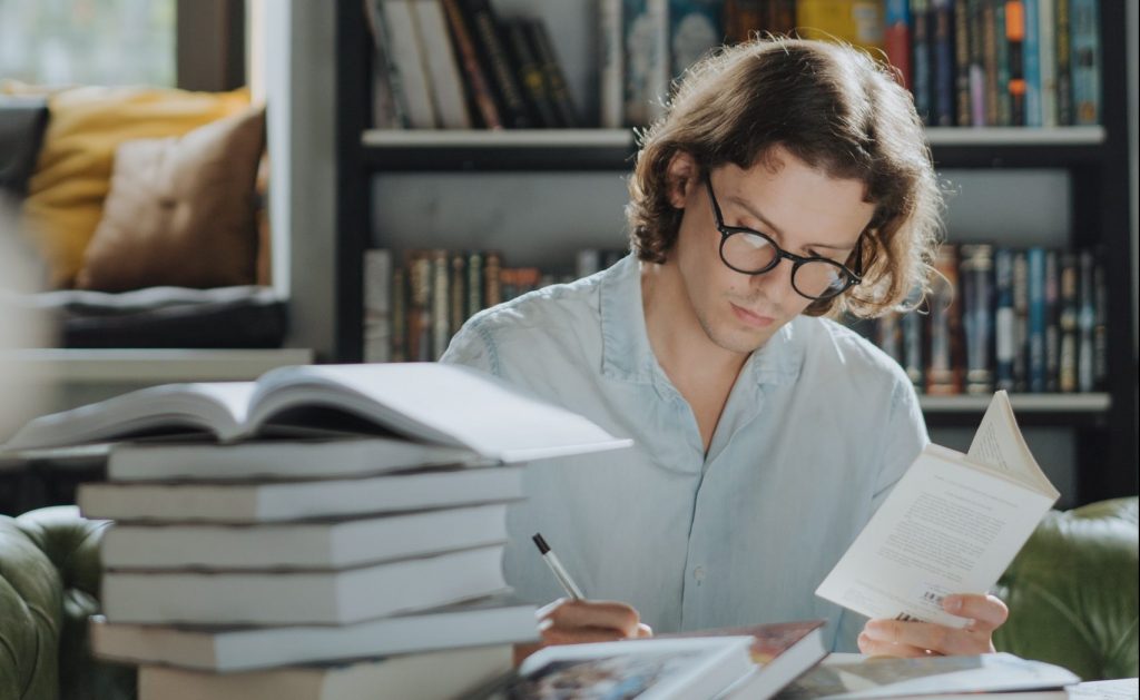 Man reading a book and writing notes